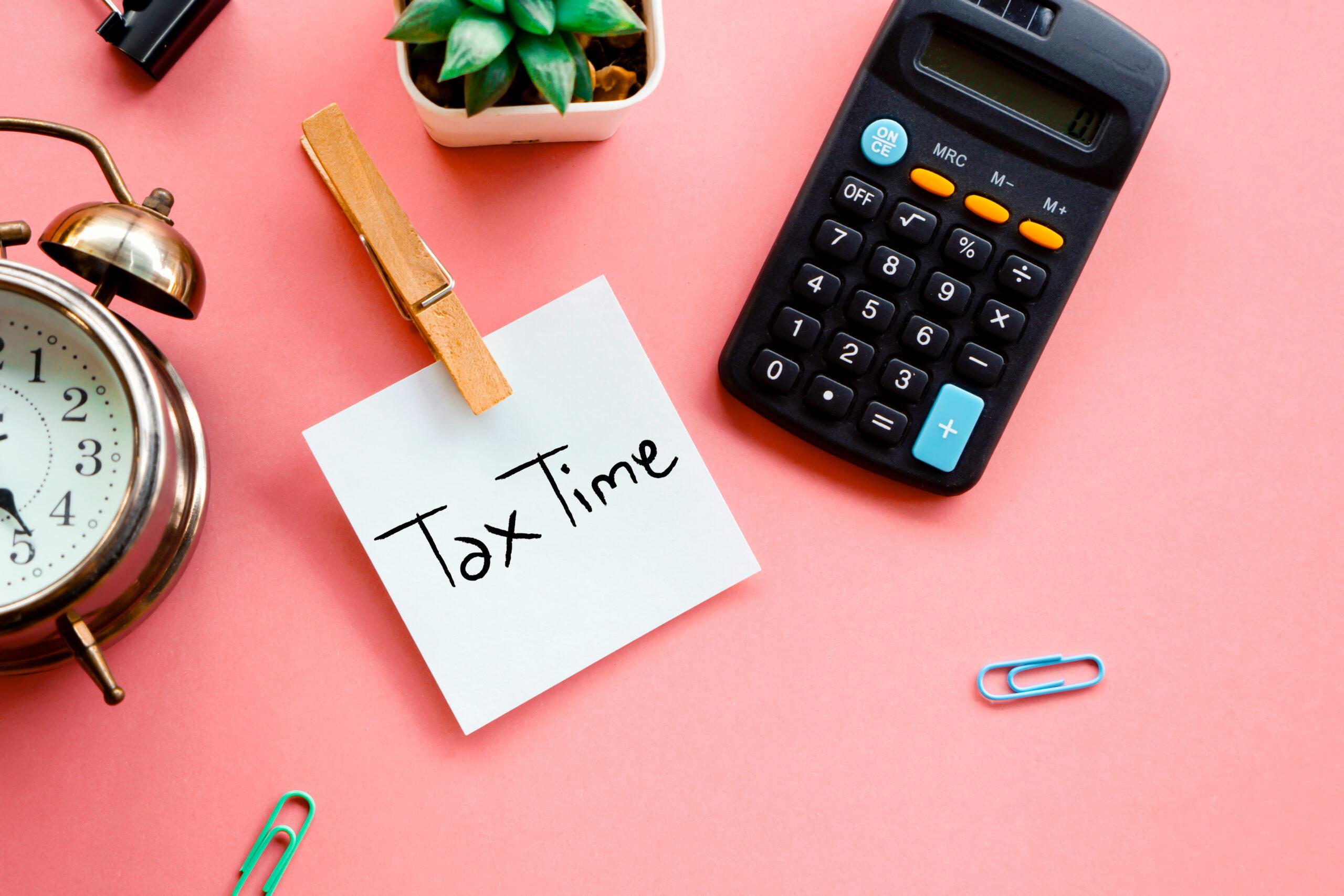 a desk with a laptop and financial documents, holding a pen and reviewing paperwork, representing a stress-free approach to a stress free tax season.